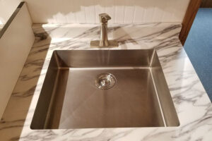 Modern white and grey laminate kitchen sink countertops with a metal single basin sink and metal faucet in Springfield, Illinois