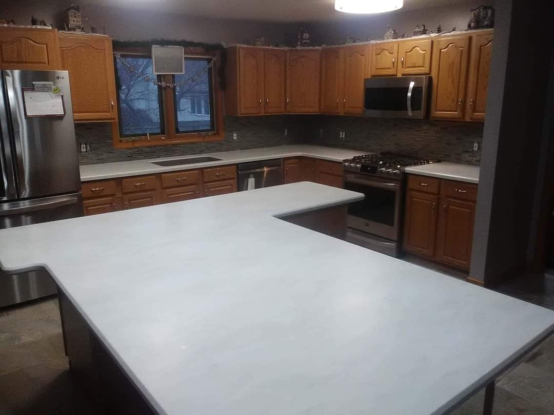White, seamless countertop island sitting within a modern kitchen.