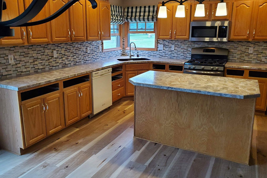 Residential kitchen in Springfield, IL with laminate countertops and a farmer’s sink. Light wood-colored countertops and an island.