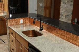 A residential kitchen with brand new black and grey-colored quartz countertops, an under-mount sink, and a black faucet in Taylorville, IL.