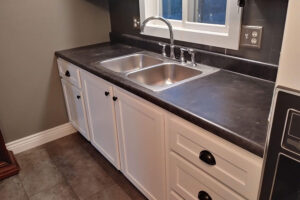 White kitchen cabinets with a dark-colored countertop and brass cup pull handles for new cabinets in Champaign, IL.