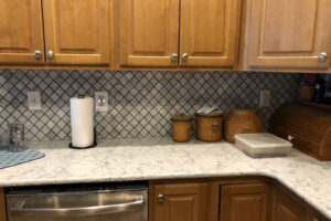 A residential kitchen in Champaign, IL with white and grey countertops and round knobs on newly installed cabinets.