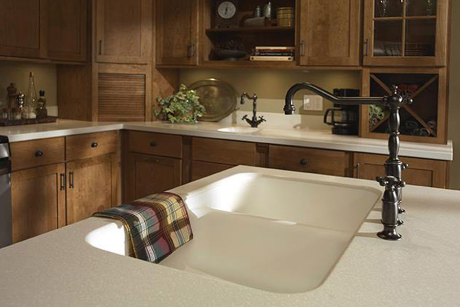 A white solid surface countertop in a residential kitchen with wood cabinets in Decatur, IL that is available in a variety of custom options.