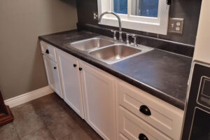 A dual basin stainless steel sink installed into a black countertop in a residential home in Glenarm, IL with increased space for cooking.