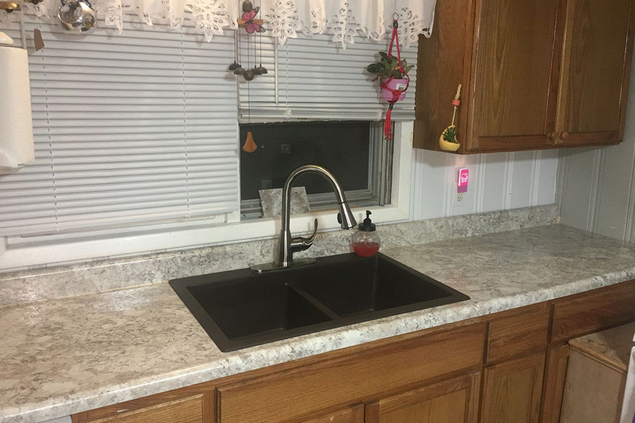 A black drop-in sink installed on a brand-new countertop with a pull-down faucet in a residential kitchen in Glenarm, IL