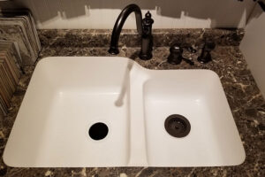 A white under-mount sink with a place three-hole mounted faucet in a residential kitchen in Glenarm, IL.