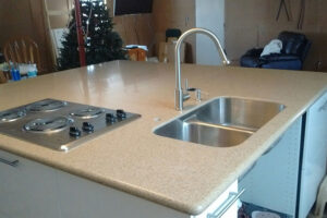 A beautiful solid surface countertop installed on an island in a residential home in Glenarm, IL with a dual basin sink.