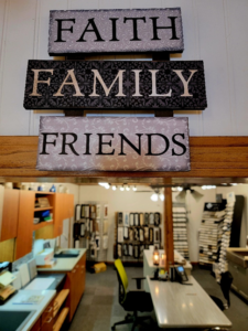A large sign that says faith, family, and friends hanging above a doorway to Ray’s Countertop Shop’s showroom in central Illinois.