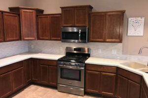 A beautiful residential kitchen in Springfield, IL with a white solid surface countertop, brown cabinets, and stainless-steel appliances.