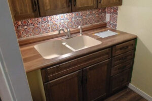 A brand new bisque acrylic sink installed in Glenarm, IL with butcherblock countertops and brown cabinets from Ray’s Countertop Shop.