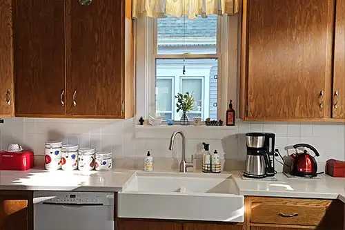 RAY'S COUNTERTOP SHOP INC. - White apron sink around brown cabinets in a Springfield IL, kitchen.