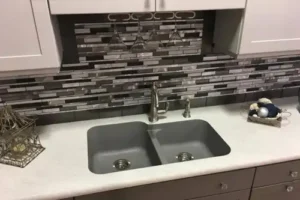 RAY’S COUNTERTOP SHOP INC. - A kitchen in Springfield IL, with bold backsplash tiles behind a kitchen sink and white countertops.