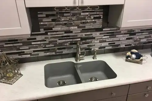 RAY’S COUNTERTOP SHOP INC. - A kitchen in Springfield IL, with bold backsplash tiles behind a kitchen sink and white countertops.