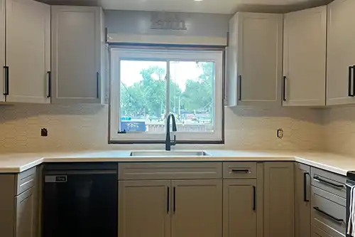 RAY’S COUNTERTOP SHOP INC. - A kitchen in Springfield, IL, with a new matte black faucet and cabinet hardware next to white countertops.