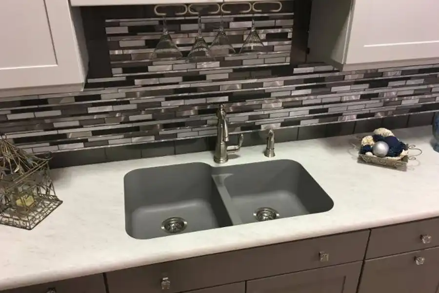 RAY’S COUNTERTOP SHOP INC. - A kitchen in Springfield IL, with bold backsplash tiles behind a kitchen sink and white countertops.
