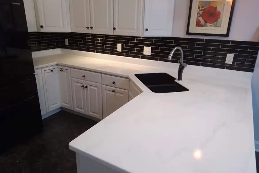 A beautiful white solid surface countertop design by Ray’s Countertop Shop, Inc. inside of a modern kitchen with brick-style tile backsplash in a Central Illinois home.